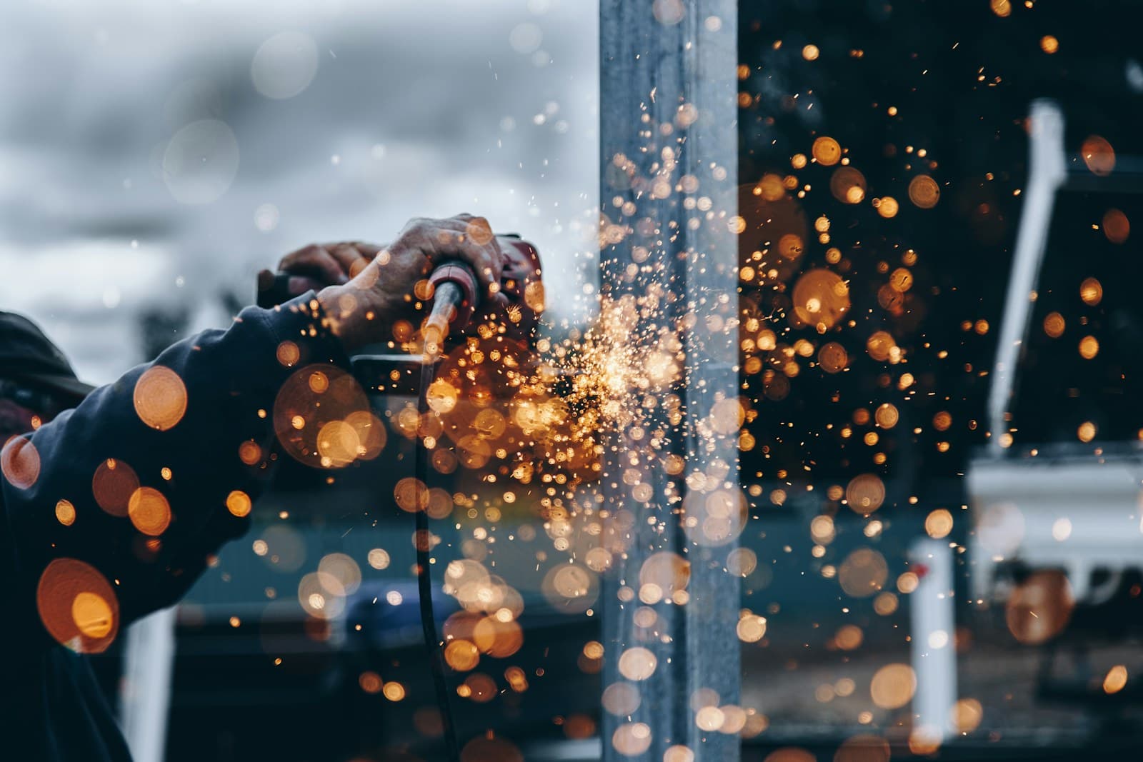 Technician grinding metal, furnace-orange sparks in the foreground