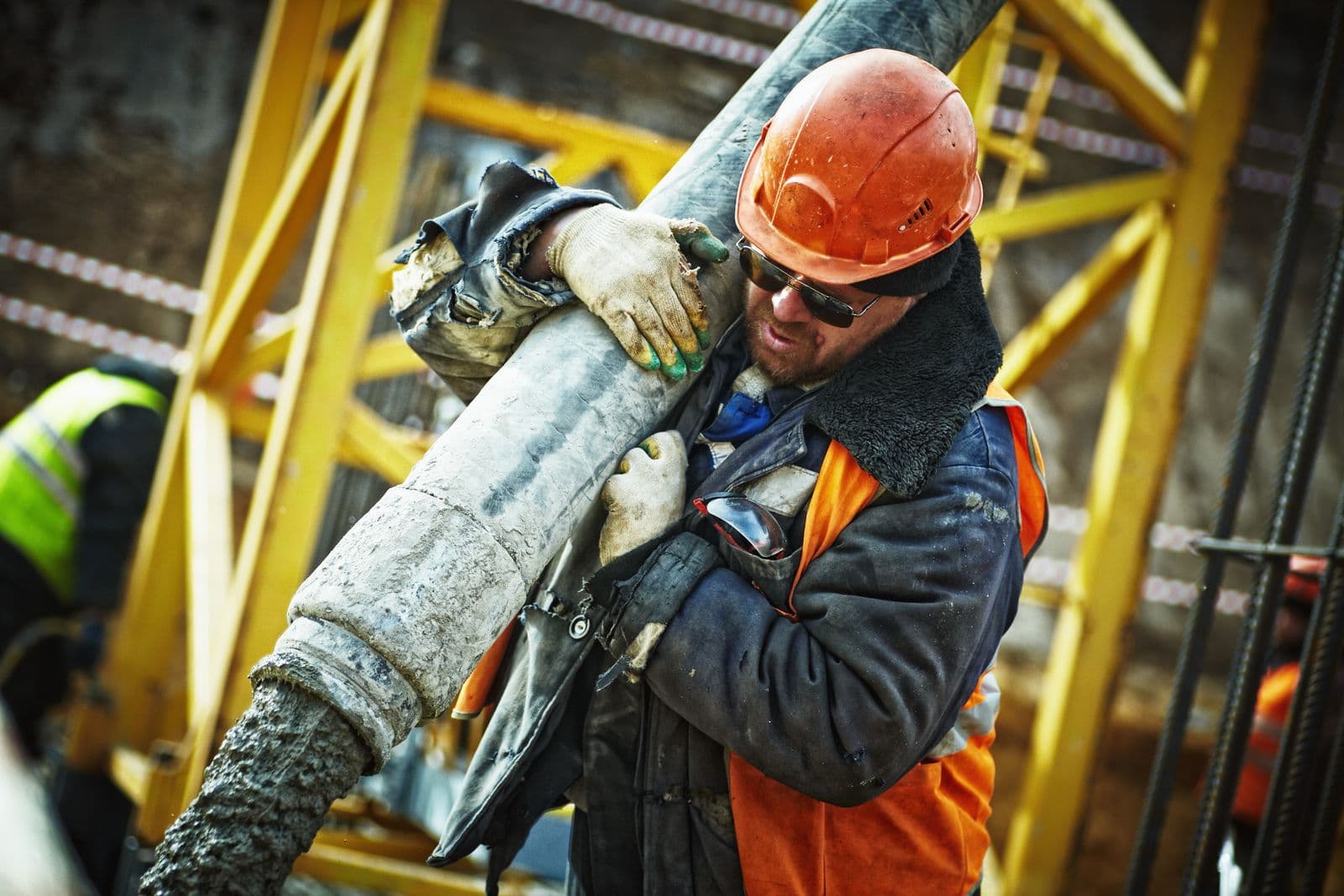 Installer carrying a large pipe on a commercial site